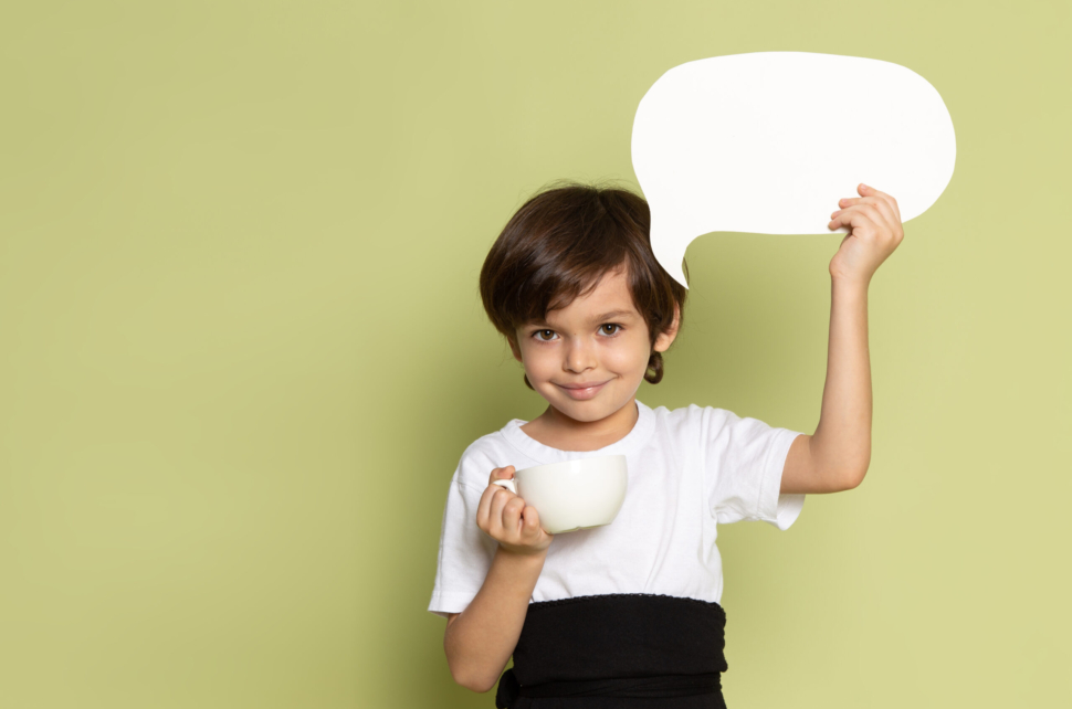front-view-smiling-child-boy-white-t-shirt-holding-white-sign-stone-colored-space